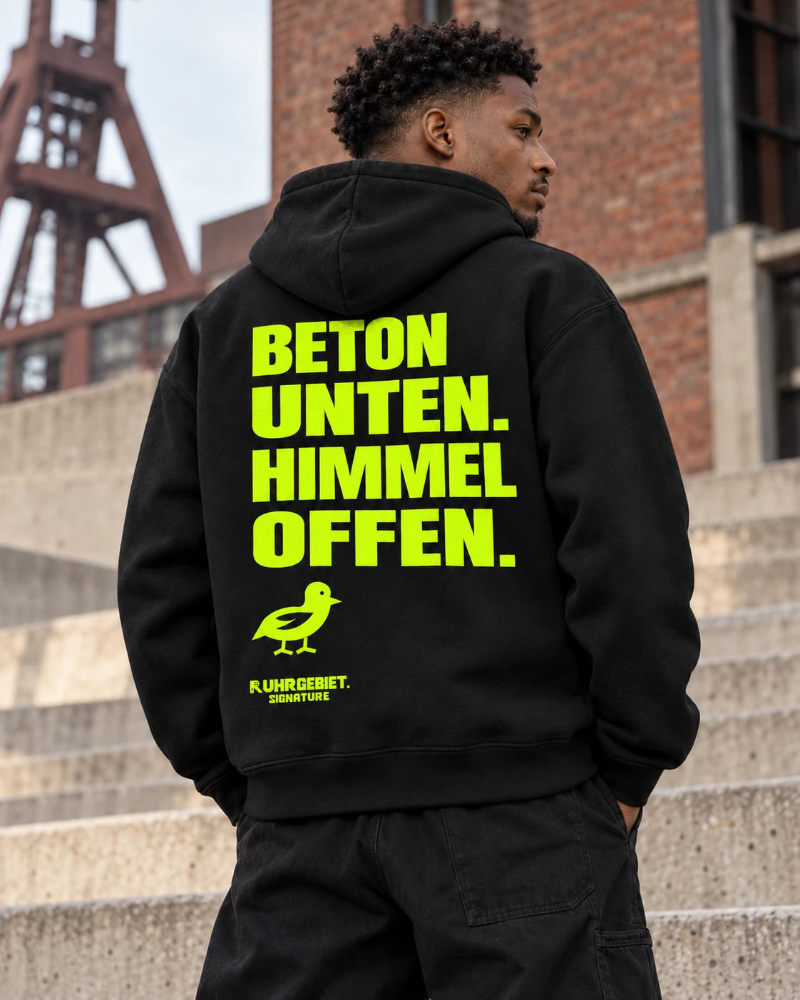 BETON UNTEN. HIMMEL OFFEN. – Neonmotiv an einem fiktiven Model bei Tageslicht. KI-Produktillustration.