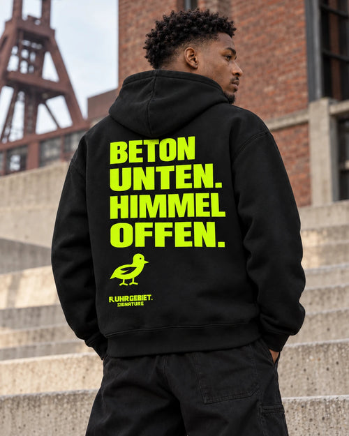 BETON UNTEN. HIMMEL OFFEN. – Neonmotiv an einem fiktiven Model bei Tageslicht. KI-Produktillustration.
